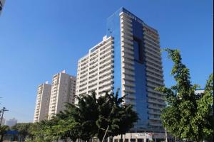 a tall blue building with trees in front of it at Apartamento Studio em São Bernardo in São Bernardo do Campo