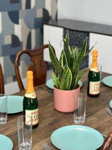 uma mesa com duas garrafas de champanhe e um vaso de plantas em Newly renovated, spacious East London home em Seven Kings