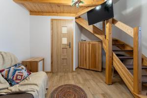 a living room with a staircase with a flat screen tv at Dom Krawca - pod Chojnikiem in Jelenia Góra