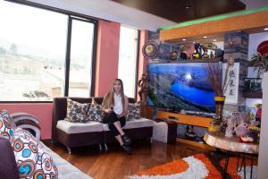 a woman sitting on a couch in a living room at HOTEL MADURAI in Ambato