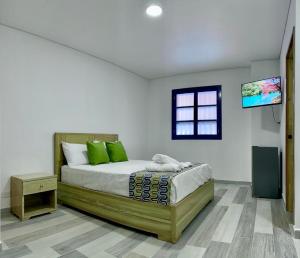 a bedroom with a bed with a tv on the wall at ALTO VERDE HOTEL in Guatapé