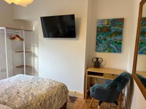 a bedroom with a bed and a desk with a television on the wall at Double Room at Minster Cottage in Kings Lynn