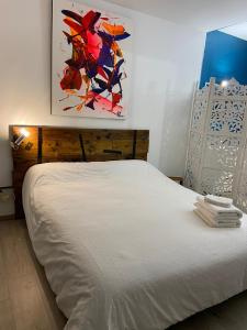 a white bed in a bedroom with a painting on the wall at La Chambre du Patio in Le Luc