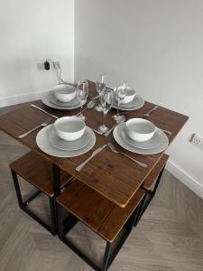 a wooden table with plates and wine glasses on it at Luxury Studio Apartment in Manchester