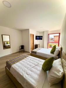 sypialnia z dwoma łóżkami i telewizorem na ścianie w obiekcie ALTO VERDE HOTEL w mieście Guatapé