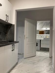 a kitchen with white cabinets and a white door at Apartament Pogodno in Szczecin