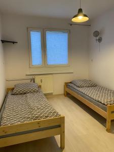 two beds in a room with two windows at Apartament Pogodno in Szczecin