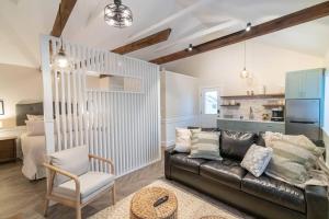 a living room with a black leather couch and a bedroom at AmishGuestCottage~cozystudio~hottub~patio in Gordonville