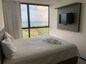 a bedroom with a bed with a large window at BARRA FLATS BY LOUI in Recife