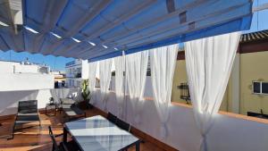 balcón con cortinas blancas, mesa y sillas en Ático la Azotea con terraza PRIVADA, en Sevilla
