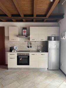 a kitchen with white cabinets and a stainless steel refrigerator at Appartamento vicino Forum Assago & Humanitas in Rozzano