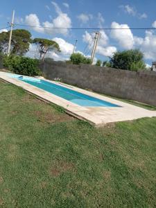 a swimming pool in a yard next to a wall at Cabañas "Las Acacias" in Villa Santa Cruz del Lago