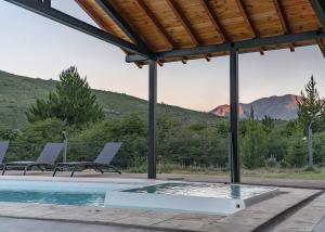 una piscina con 2 tumbonas y vistas a las montañas en La Finca Hostel de Montaña - Habitación Laguna en San Carlos de Bariloche