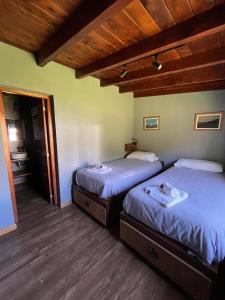 Habitación con 2 camas individuales y suelo de madera. en La Finca Hostel de Montaña - Habitación Laguna en San Carlos de Bariloche