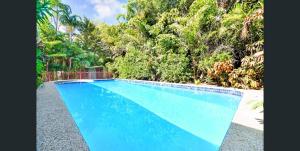uma piscina azul com árvores ao fundo em Tropica Bliss: 2.5km to CBD em Stuart Park