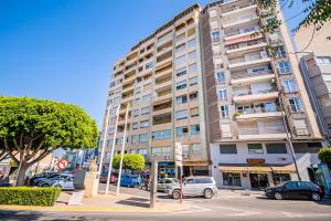 a tall building with cars parked in front of it at Vila Playa in Villajoyosa