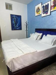 a bedroom with a large white bed with a blue wall at Studio meublé Corniche Mermoz in Dakar