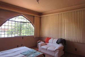 ein Wohnzimmer mit einem Sofa und einem Fenster in der Unterkunft CASA SUL DE MINAS ITAJUBA COM PISCINA, CHURRASQUEIRA E MUITO ACONCHEGO in Itajubá