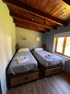 dos camas sentadas una al lado de la otra en una habitación en La Finca Hostel de Montaña - Habitación Laguna en San Carlos de Bariloche