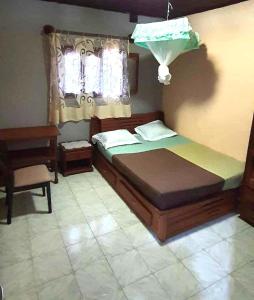 una camera con un letto e una sedia e una finestra di Maison d'hôtes Villa Mont du Pèlerin à Toamasina Madagascar a Toamasina