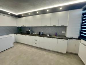 a kitchen with white cabinets and a sink at D&D New Residence in Piteşti