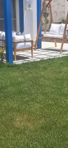 a patio with a chair and a table and some grass at توين بماونتن فيو الساحل الشمالى in Dawwār Abū Maḩrūs
