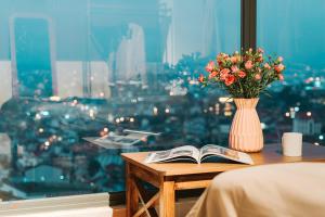 einen Tisch mit einer Vase Blumen und einem Buch in der Unterkunft Miền Sương Khói Homestay Đà Lạt in Da Lat