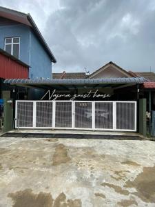 a building with a fence with a sign on it at Najma guest house in Kota Bharu