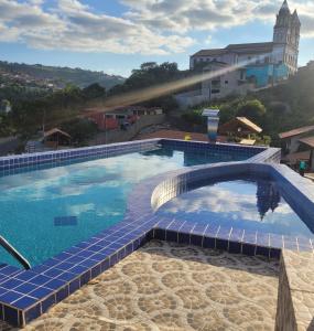 a swimming pool with a blue tile floor and a bridge at CHALES DA SERRA in Bananeiras