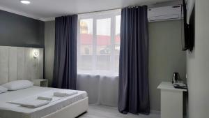 a bedroom with a bed and a window with purple curtains at SkyTerra Park Hotel in Novy Afon