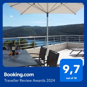 a balcony with an umbrella and a table and chairs at Istra-Hvar Luxury Penthouse in Rabac