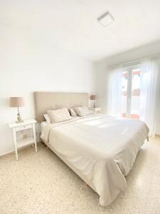 a white bedroom with a white bed and a window at Townhouse w/sea view & garden in Estepona