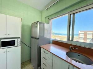 een keuken met een koelkast, een wastafel en een raam bij Almenara Beach in Almenara