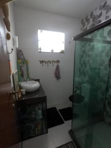 La salle de bains est pourvue d'une douche en verre et d'un lavabo. dans l'établissement Casa Temporada em Praia Linda., à São Pedro da Aldeia