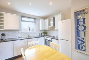 a kitchen with a wooden table and a white refrigerator at Kurnell Cottage, Staithes in Staithes +12 photos
