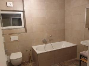 y baño con bañera, aseo y lavamanos. en Helle 3 Zimmer Souterrainwohnung in einem Neubau-Villa, en Múnich