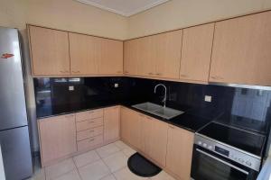 a kitchen with wooden cabinets and a sink and a refrigerator at LagoZervo Short Term Stay in Kandhíla