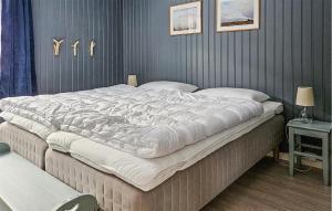 a large white bed in a bedroom with a wall at Lovely Apartment In Rjukan in Rjukan +2 photos