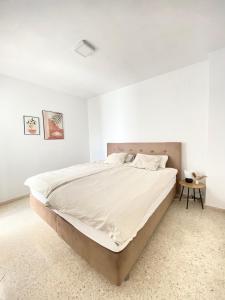 Un dormitorio blanco con una cama grande y una mesa en Townhouse w/sea view & garden, en Estepona