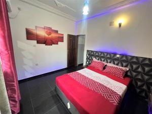 een slaapkamer met een rood en wit bed met paarse verlichting bij The Yafé Bastos 13 in Yaoundé