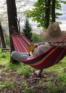 a person sitting in a hammock with a hat at Wietorówka in Lubomierz
