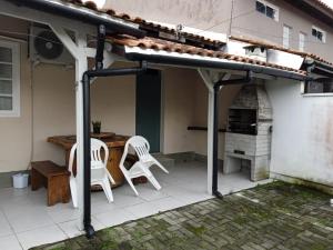 pérgola con 2 sillas y mesa en el patio en Casa no Campeche para veraneio com internet, en Florianópolis