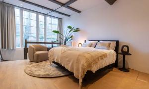 een slaapkamer met een bed, een stoel en ramen bij Hofje van Sint Jan in Gouda