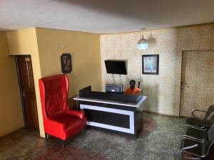 Ein Mann, der auf einem Klavier in einem Zimmer mit einem roten Stuhl sitzt. in der Unterkunft ClinClia Hotel2 in Ibadan