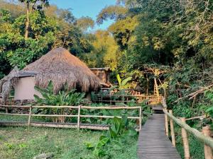 a wooden path leading to a hut with a thatch roof at Las Cabañas del Rio in Minca