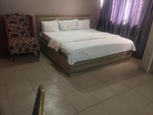 a bedroom with a bed and a chair in it at ClinClia Hotel2 in Ibadan