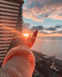 a large building with the sunset in the background at Luxury PANORAMA sea view apartment & Central Batumi in Batumi