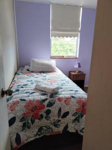 - une chambre avec un lit doté d'un couvre-lit floral et d'une fenêtre dans l'établissement DEPARTAMENTO COSTANERA PELLUCO, PUERTO MONTT, à Puerto Montt