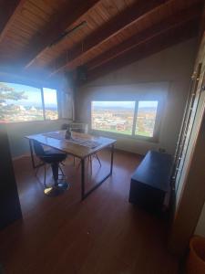 een kamer met een tafel, 2 stoelen en ramen bij Ohana in Ushuaia