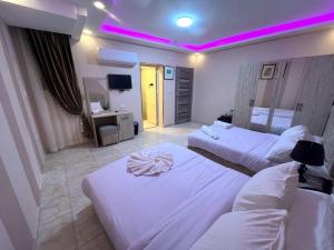 Habitación de hotel con 2 camas y luz morada en Pyramids Nun INN en El Cairo